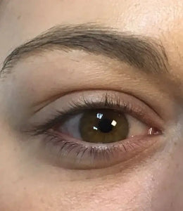 Close-up van een gezond bruin oog met verzorgde wenkbrauw, natuurlijke huid