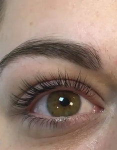 Close-up van een groen oog met volle, natuurlijke wimpers en een verzorgde wenkbrauw.